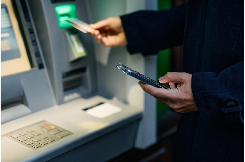 Persona insertando una tarjeta bancaria en la ranura de un cajero automático